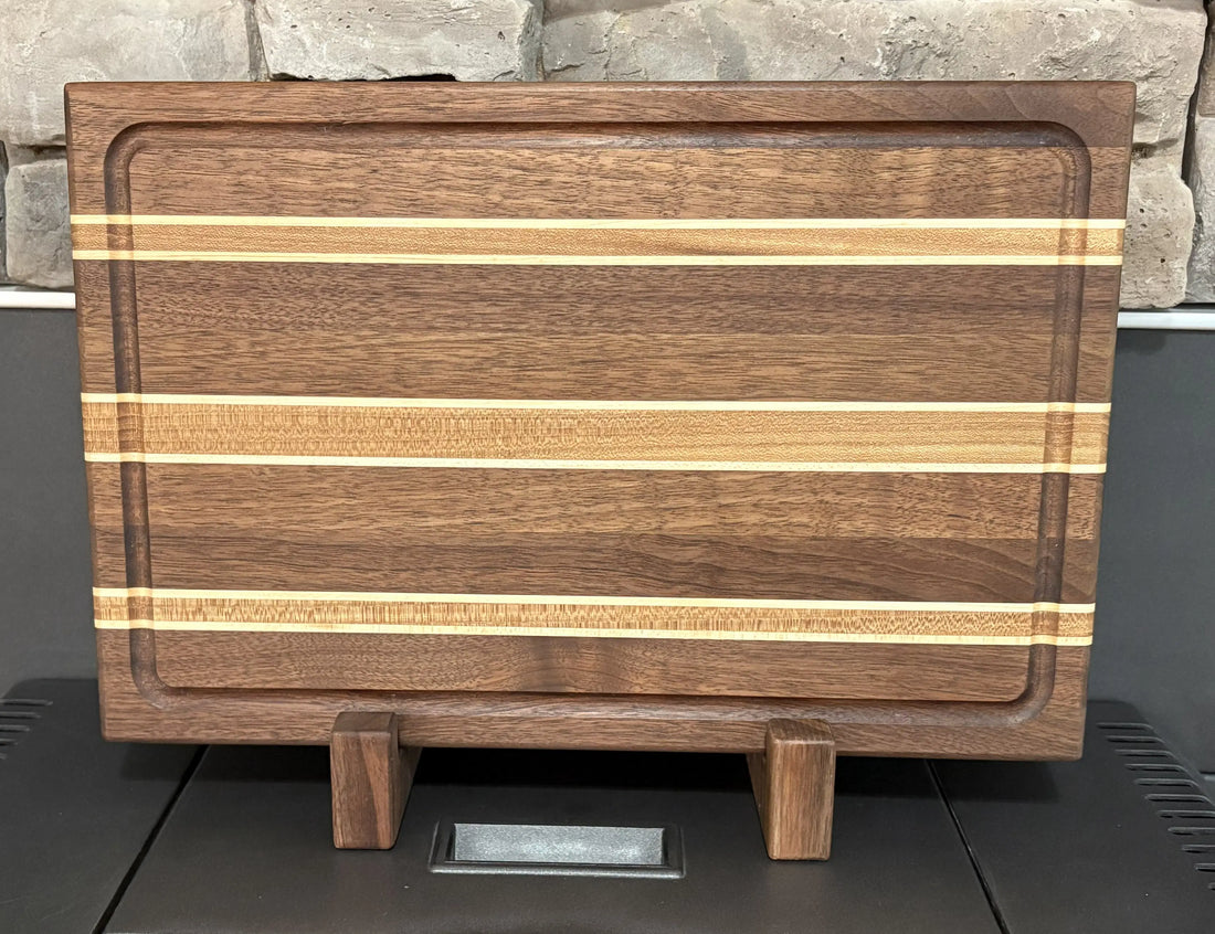 Handcrafted walnut and maple cutting board displayed on a wooden stand